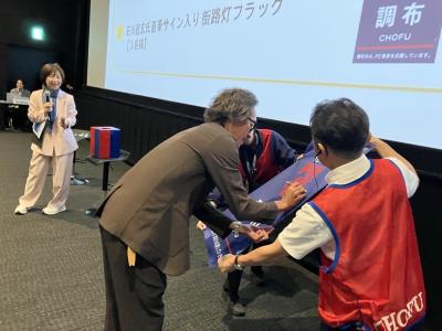 石川氏が景品にサインを入れる様子